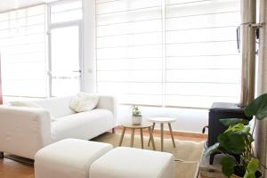 una sala de estar con muebles blancos y ventanas grandes. en Apartamentos Teixoeira, en Artes