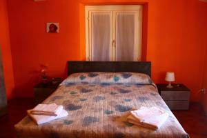 ベッラーノにあるAlbergo Del Lagoのオレンジ色の壁のベッドルーム1室、ベッド1台(タオル2枚付)