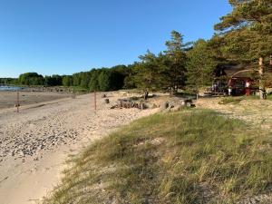 uma praia arenosa com uma casa e árvores nela em sun& relax- Cabynhouse em Syytme