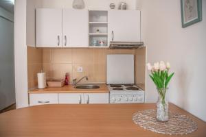 a kitchen with white cabinets and a table with a vase of flowers at Stella Modern Apartment 2 in Novi Sad