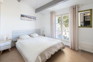 - une chambre blanche avec un lit et une fenêtre dans l'établissement Appartement Ombrine, à Saint-Martin-de-Ré