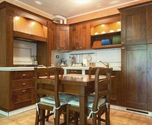 una cocina con armarios de madera y una mesa y sillas de madera. en Appartamento con Giardino e Box in Valmalenco en Torre di Santa Maria