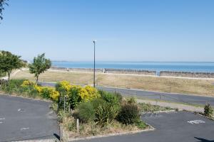 un parking vide avec l'océan en arrière-plan dans l'établissement Appartement Ombrine, à Saint-Martin-de-Ré