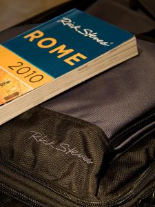 ローマにあるSuite Opera Roomsのスーツケースの上に本が座っている
