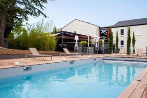 a swimming pool with two chairs and a building at Logis Hotel Relais Saint Jacques - Châteauroux in Déols