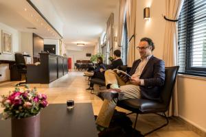 a man sitting in a chair reading a book at Hotel Kasteel Solhof in Aartselaar