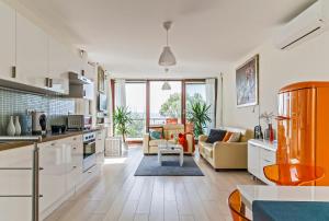 a kitchen with white cabinets and a living room at Panoramic Art Apartment with jacuzzi in Balatonlelle