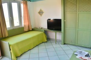 1 dormitorio con 1 cama y TV. en Casa Mare Cala Rossa, en Trinità dʼAgultu