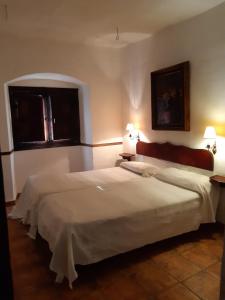 a bedroom with a large white bed with two lamps at El Aleznal in Trujillo