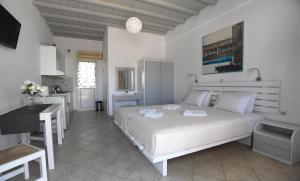 a white bedroom with a bed and a kitchen at Nostos Beachfront Apartments & Studios in Agios Ioannis