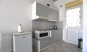 a kitchen with white cabinets and a stove and a refrigerator at Nostos Beachfront Apartments & Studios in Agios Ioannis