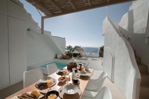 a table with food on a balcony with a pool at The Globe Suites Villa in Fira