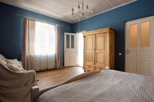 a bedroom with blue walls and a bed and a chair at Karlamuiza Country Hotel in Kārļi