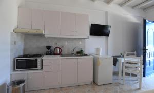 a kitchen with white cabinets and a microwave at Nostos Beachfront Apartments & Studios in Agios Ioannis