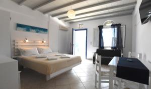 a bedroom with a large bed and a table and a desk at Nostos Beachfront Apartments & Studios in Agios Ioannis