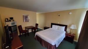 a hotel room with a bed and two chairs at Comox Valley Inn & Suites in Courtenay