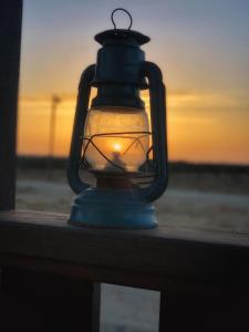 ein Licht auf einem Geländer mit Sonnenuntergang im Hintergrund in der Unterkunft צימר מול השקיעה in Retamim