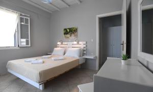 a white bedroom with a bed and a window at Nostos Beachfront Apartments & Studios in Agios Ioannis