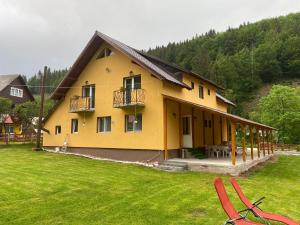 a yellow house with a patio and a grass yard at Casa Natalia Raisa Arieșeni in Arieşeni
