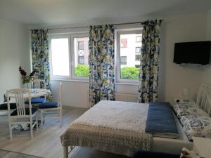 a bedroom with a bed and a table and two windows at Pokoje Gościnne PLUS in Ustka