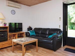 a living room with a black leather couch and a coffee table at 6 person holiday home in Gedser in Gedser