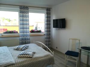 a room with a table and a tv and two windows at Pokoje Gościnne PLUS in Ustka