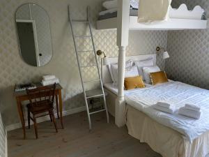 a bedroom with a bed and a desk with a mirror at Café Mandeltårtan B&B VillaFloraViola in Ronneby