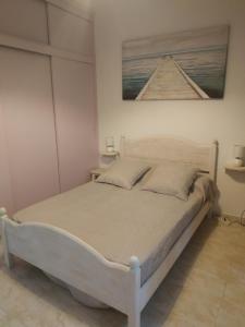 1 cama blanca en un dormitorio con una foto en la pared en Paradis, en Morro del Jable