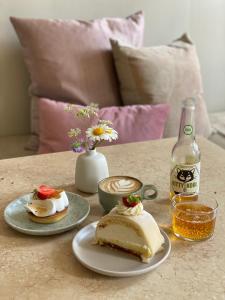 a table with two plates of cake and a bottle of beer at Café Mandeltårtan B&B VillaFloraViola in Ronneby