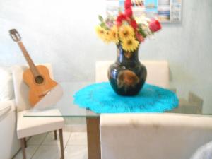 un jarrón de flores en una mesa de cristal con una guitarra en Casa Rodriguez " Expo Center Norte ", en São Paulo