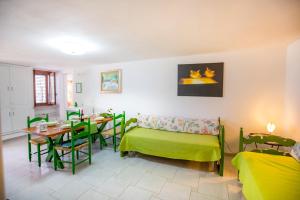 a living room with a table and a green couch at Casa Bianca Rais Gerbi in Finale