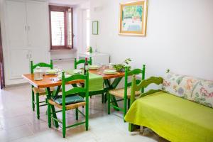a dining room with a table and green chairs at Casa Bianca Rais Gerbi in Finale