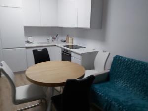 cocina pequeña con mesa y sofá azul en Przymorze Spectrum Apartment for you z halą garażową, en Gdansk