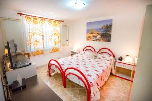 a bedroom with a red bed and a television at Casa Bianca Rais Gerbi in Finale