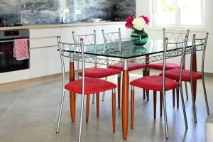 een glazen tafel met rode stoelen en een vaas met bloemen bij Villa Thalia in Bibinje