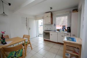 a kitchen with white cabinets and a table and a table and chairs at Fewo Kaiser Am Lindenpark - Free Wifi in Kühlungsborn +6 photos