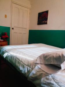 1 dormitorio con cama blanca y pared verde en Nápoles Emperador II, en Ambato