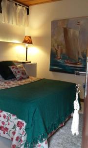 a bedroom with a bed with a green bedspread and a lamp at Regina Apartments in Morro de São Paulo