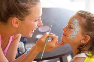 
a woman and a little girl are looking at a child's face at Insotel Club Maryland in Playa Migjorn
