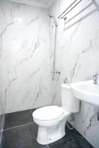 a white bathroom with a toilet and a sink at Mel's Inn Manado in Manado