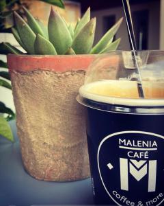 a cup of coffee sitting next to a potted plant at Malenia Hotel in Tolo