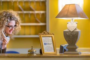 a table with a lamp and a frame and a sign at Hotel Ambasciatori in Brescia