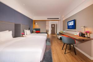 成都市にあるHoliday Inn Express Chengdu East, an IHG Hotelのベッド2台とデスクが備わるホテルルームです。