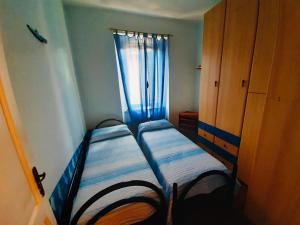 una piccola camera da letto con due letti e una finestra di Casa Lividonia a Porto Santo Stefano