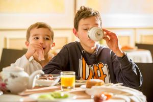 two children sitting at a table with a cup of coffee at Hotel Ambasciatori in Brescia