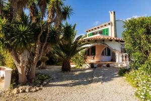 a house with palm trees in front of it at Villa Cecylia in Es Canutells