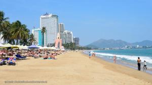 una playa con gente sentada en la arena y el océano en Boutique Hotel La Villa, en Nha Trang
