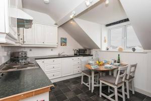 a kitchen with white cabinets and a table with chairs at HEADLANDS-2 BED-SEA VIEW APARTMENT-TREARDDUR BAY in Trearddur