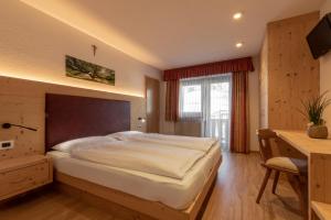 a bedroom with a large bed and a desk at B&B Apartments La Palsa in San Cassiano
