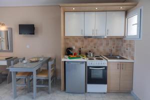 a kitchen with white cabinets and a table and a stove at eleni studios in Vlachata